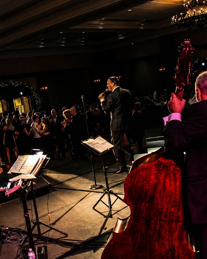 Barry Shaw singing to a packed black-tie gala floor, upright bass in the foreground