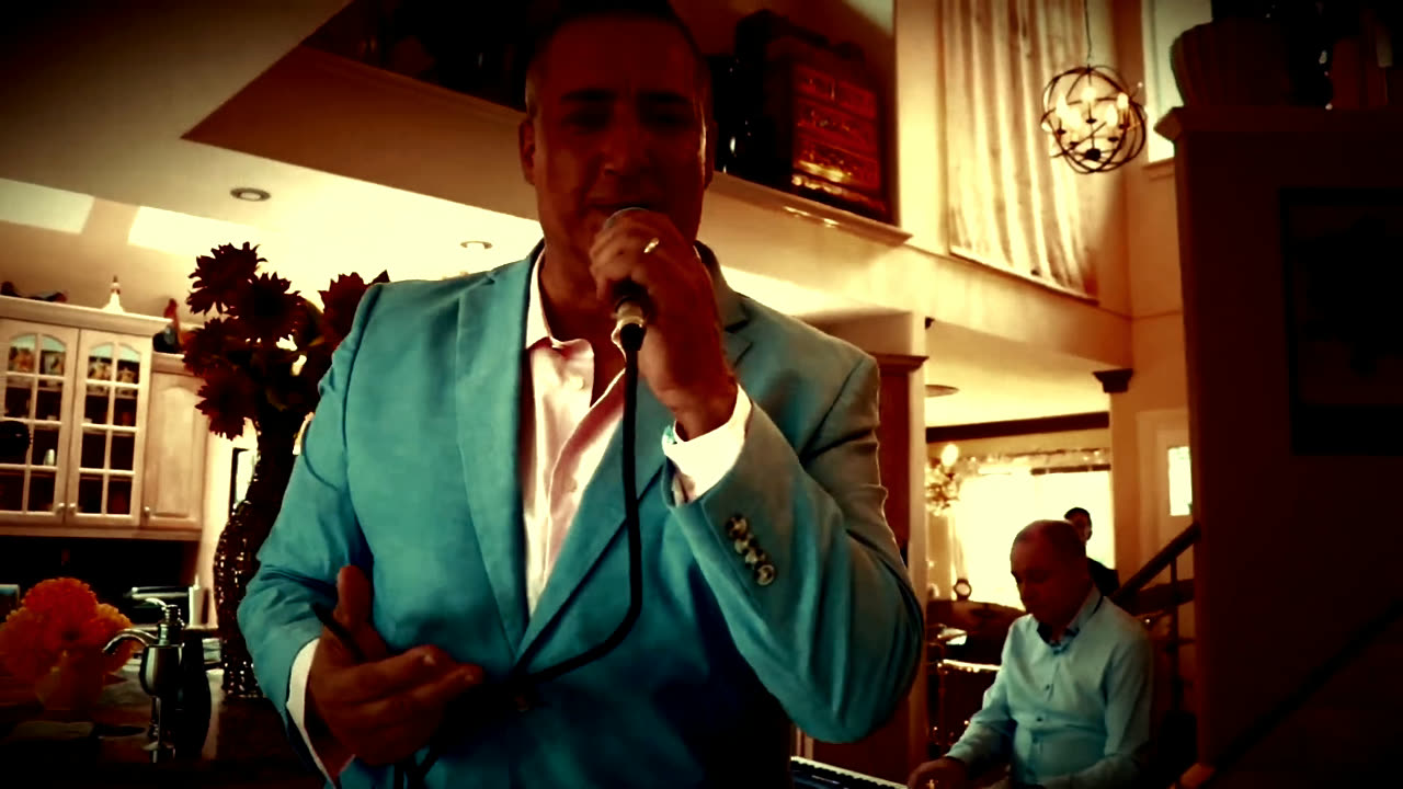 Barry Shaw singing into a handheld mic with his band behind him