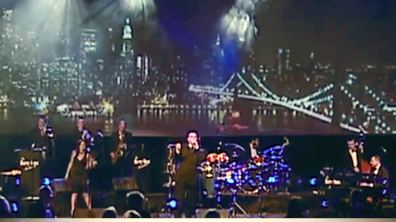 Barry Shaw centre stage with his full band under a New York skyline backdrop